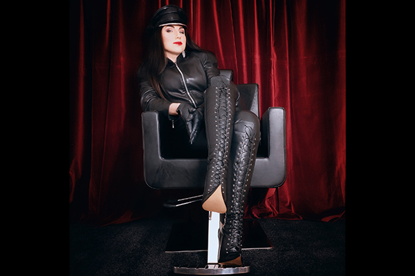 Vinyl Queen wears a leather outfit with knee-high boots by Charlotte Luxury.